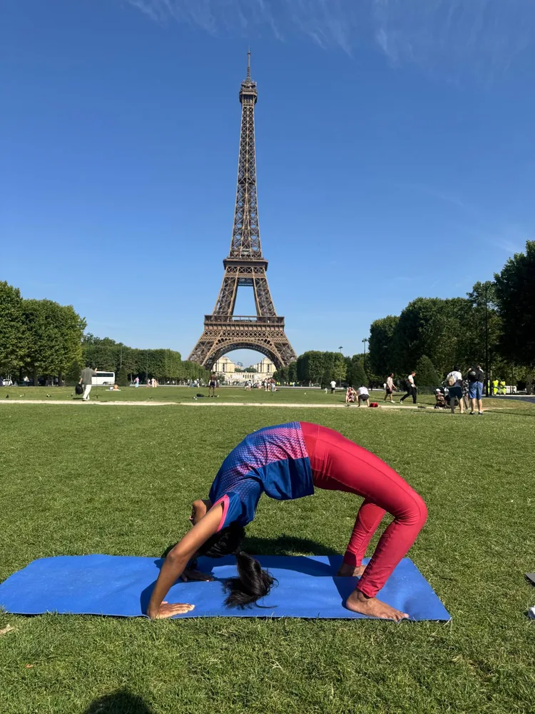 Jeevana in wheel pose on the Champ-de-Mars, Eiffel Tower behind